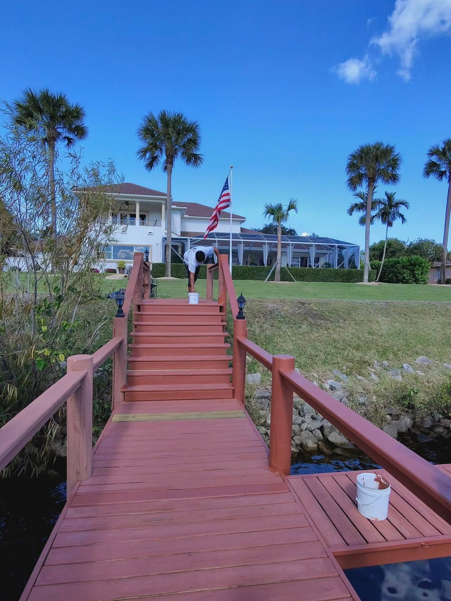 Stained wood stairs and dock walkway leading to a Treasure Coast waterfront home by Millman Services.
