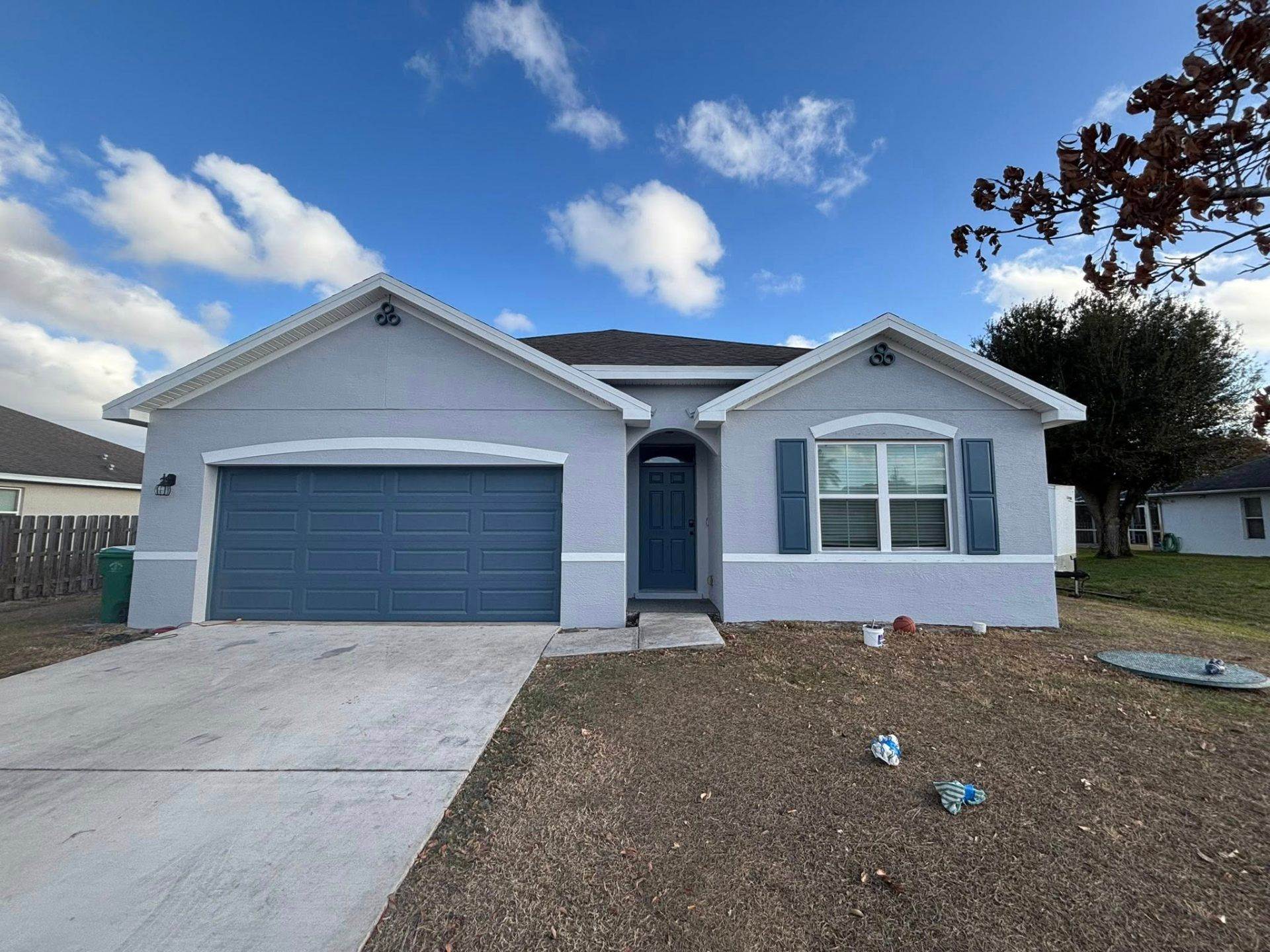 Exterior repaint of a Florida single-story home with blue accents by Millman Services.