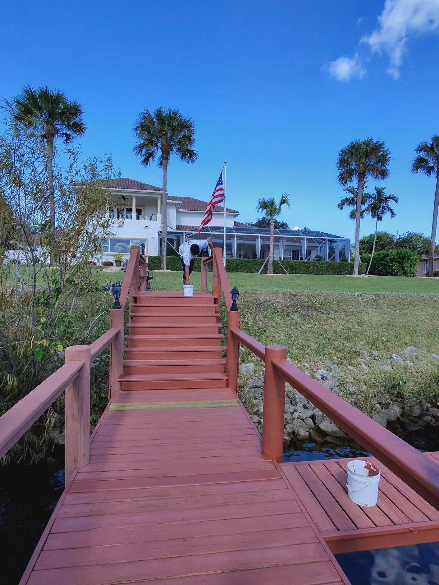Stained wood stairs and dock walkway leading to a Treasure Coast waterfront home by Millman Services.
